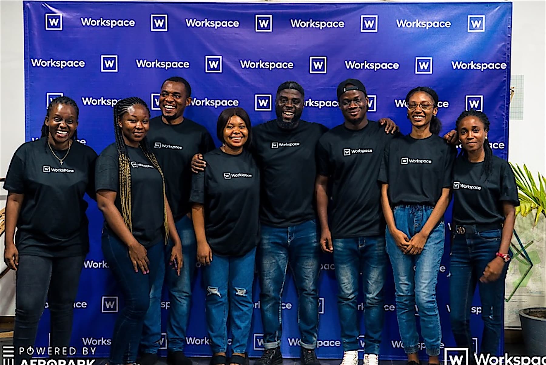 The Workspace team in branded T-shirts in front of a Workspace backdrop