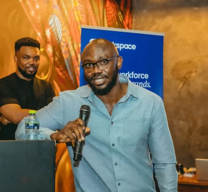 A speaker with a microphone in front of a Workspace banner