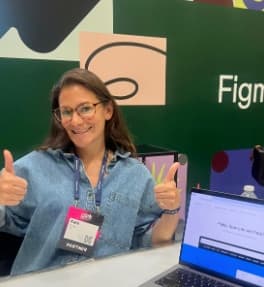 A smiling team member giving two thumbs up at the Figma stand
