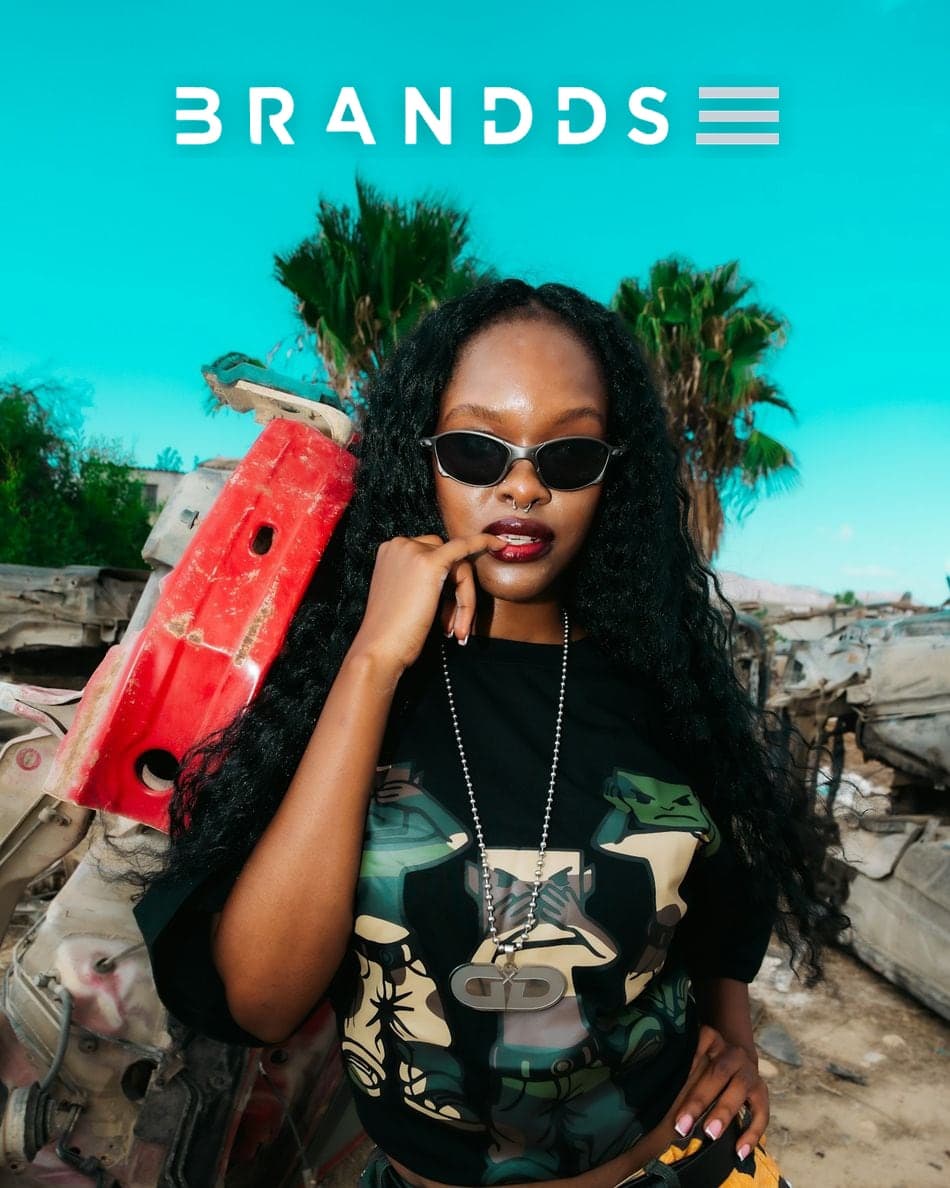 A model in streetwear and sunglasses under a bright blue sky, with the Brandds logo